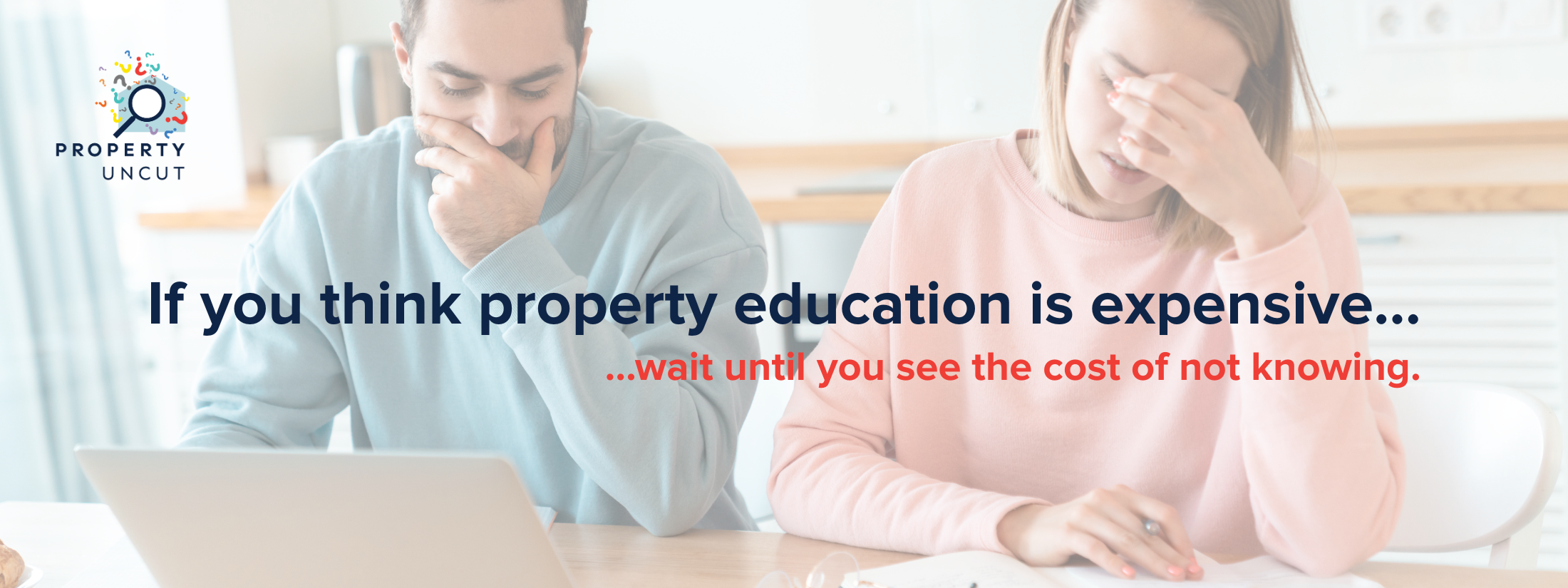 A stressed couple reviewing documents and finances at their kitchen table, representing the risks of buying property without the right education.